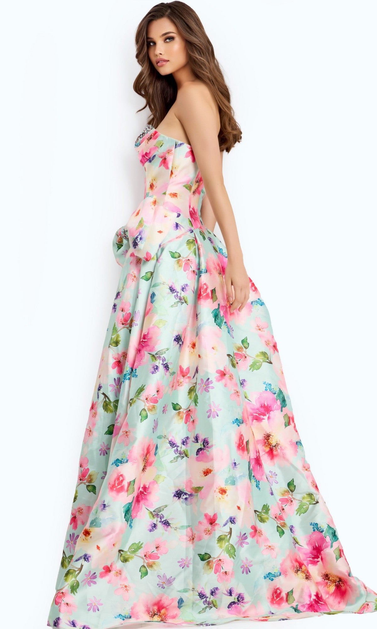 A woman wearing the Jovani 49197 long prom dress, a strapless floral A-line gown with a sweetheart neckline, stands sideways against a pastel background.